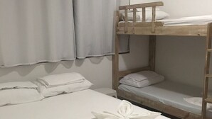 A bunk bed with white bedding, a wooden headboard, and a towel with a floral design on the lower bunk. - Chalé Feriasclub, 87 Rua da Praia, Maragogi, Brazil (Maragogi)