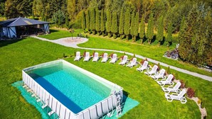 A rectangular swimming pool with a surrounding deck, surrounded by a well-manicured lawn and a row of white lounge chairs. - Single-story Holiday Home by the Pond no. 3 (Darlowo)