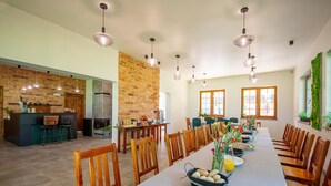 A spacious dining area with a long table, wooden chairs, and hanging pendant lights. - Single-story Holiday Home by the Pond no. 3 (Darlowo)