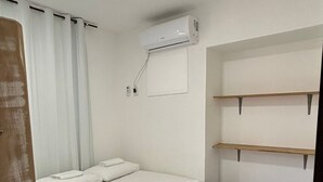 Une chambre à coucher avec un lit, un appareil de climatisation et une fenêtre avec des rideaux.