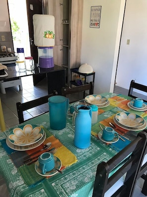 A dining area with a table set for four, featuring blue and white plates, cups, and a pitcher.