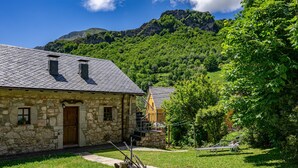Una casa de piedra con puerta de madera, una ventana pequeña y una escalera que sube a un segundo nivel.