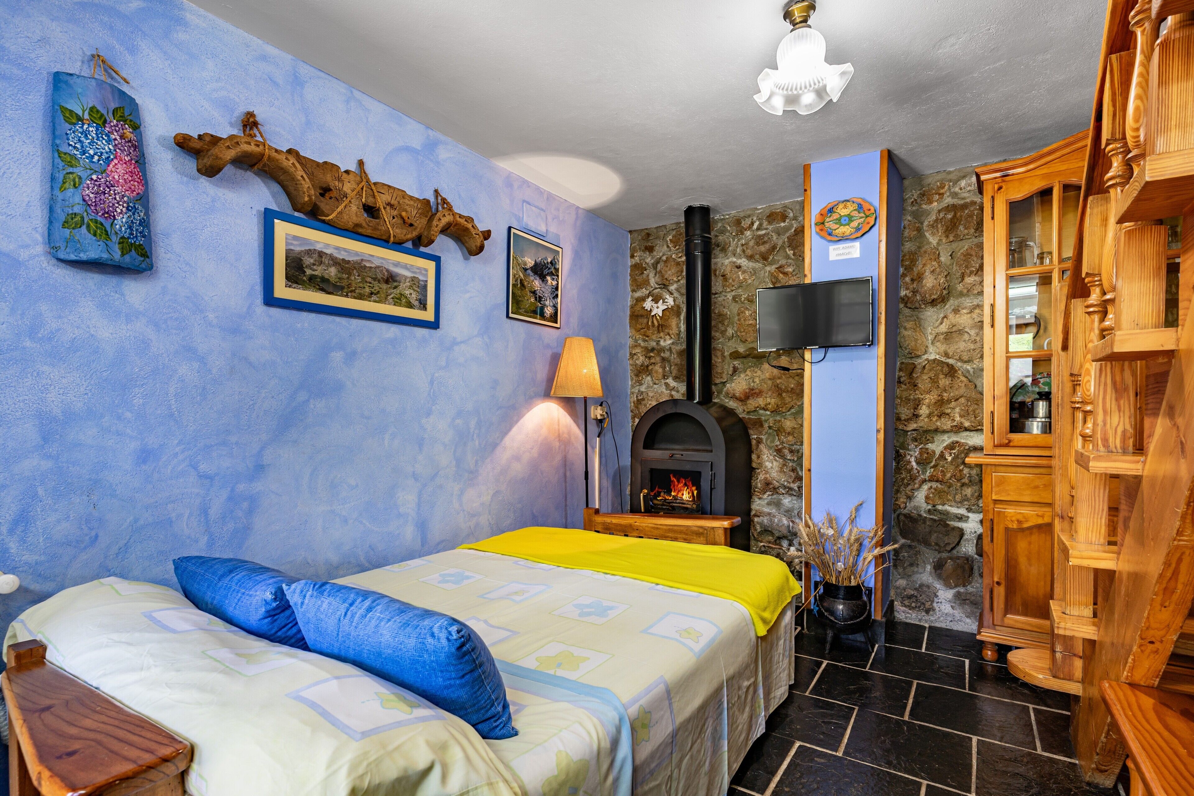 Une chambre à coucher avec un lit, une cheminée, un mur en pierre et des meubles en bois.
