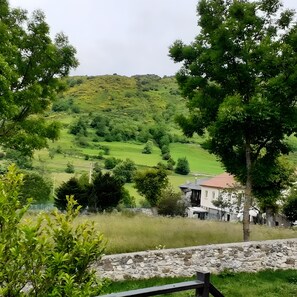 Paisaje rural con una casa, campos verdes y árboles.