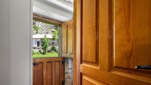 Una porta di legno con una finestra che mostra un muro in pietra e vista su una casa.