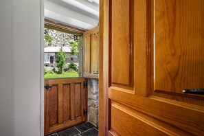 A wooden door with a window revealing a stone wall and a view of a house. - Rural house with mountain views, shared garden, and Wi-Fi (Valle de Lago)