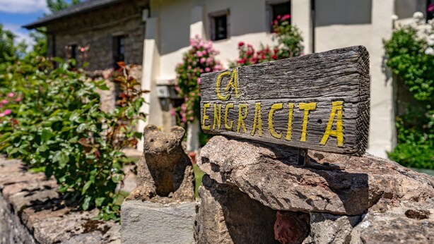 Un muro in pietra rustica con un cartello di legno che riporta la scritta 'ENCRACITA'.