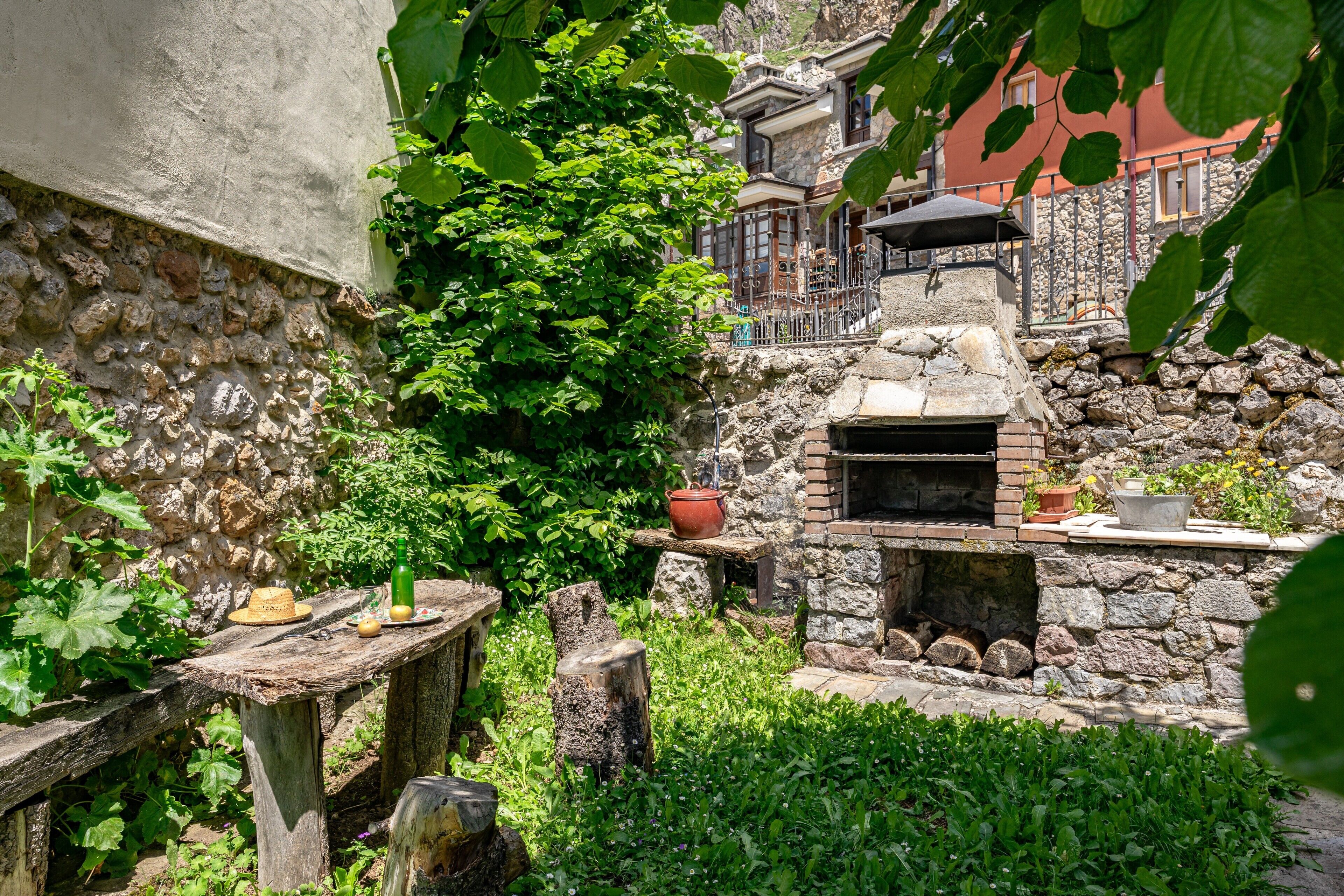 Un espacio al aire libre rústico con un horno de piedra, mesas de madera y plantas en macetas.