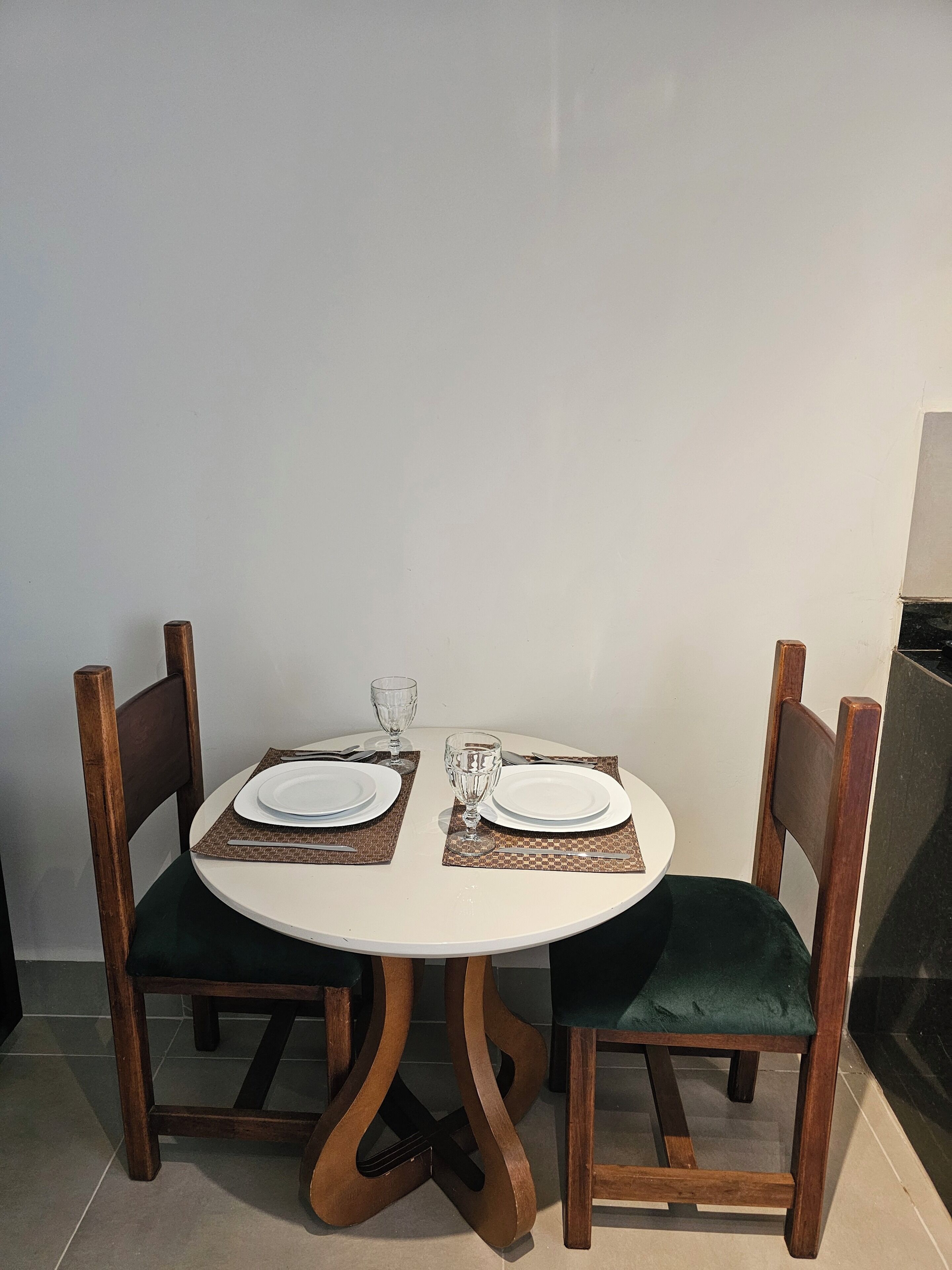 A dining table with two chairs, each with a placemat and a plate.