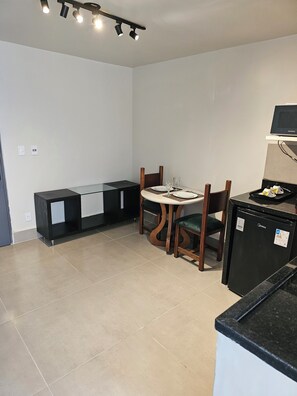 Uma cozinha moderna com geladeira, mesa de jantar com cadeiras e um banco embutido.