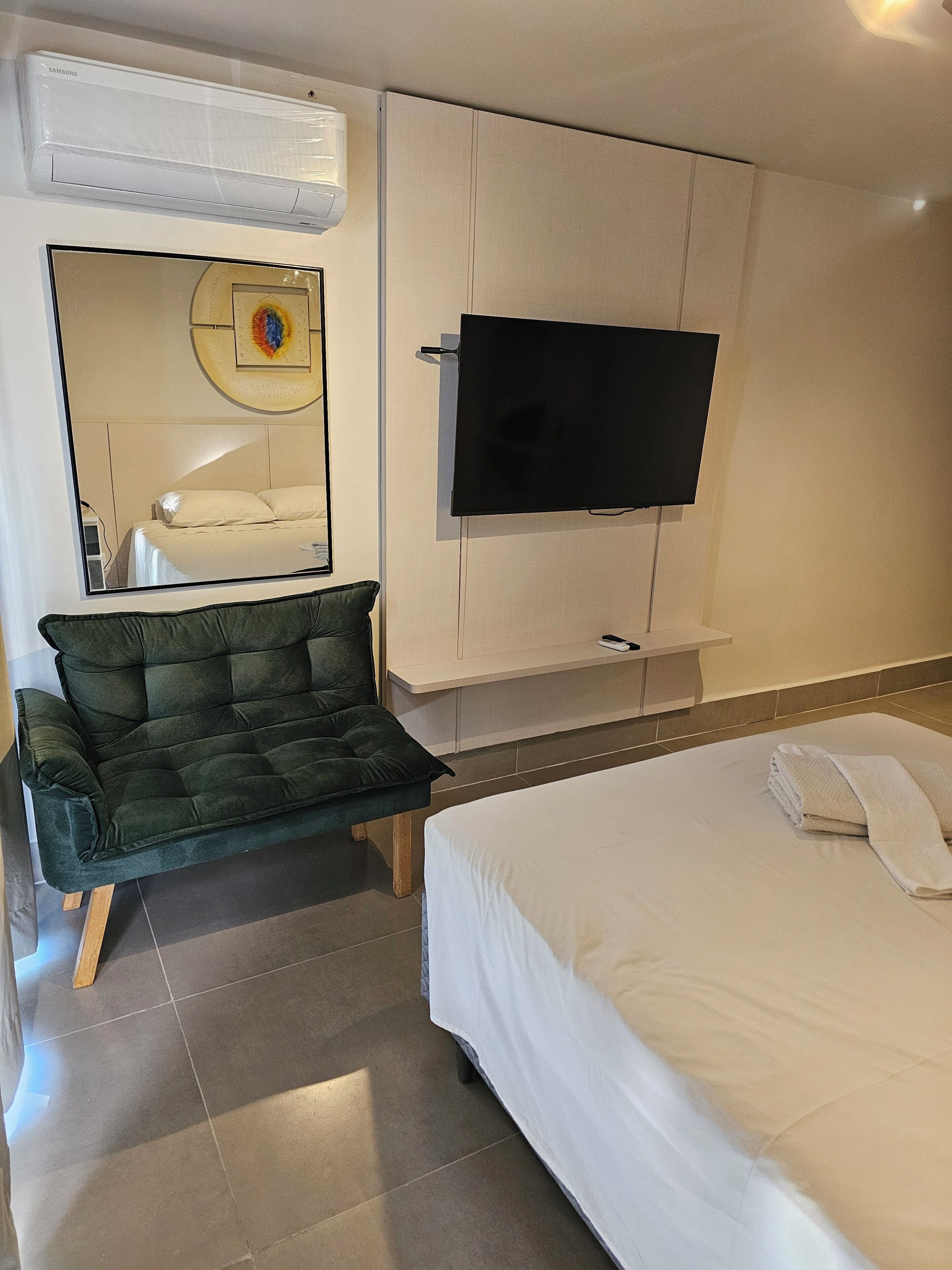 Une chambre d’hôtel équipée d’un lit, d’un canapé, d’un téléviseur fixé au mur et d’un climatiseur au plafond.