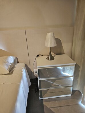 Ein Hotelzimmer mit Bett, Nachttisch mit Lampe und Ablagefläche.