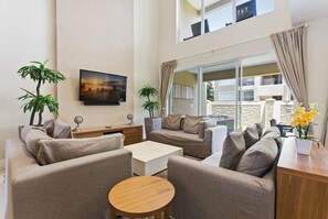 Ein modernes Wohnzimmer mit einer Sofagarnitur, einem Couchtisch und zwei Blumentöpfen.