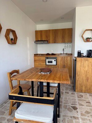 A compact kitchen with wooden cabinets, a microwave, and a dining area with a wooden table and chairs. - Apartment with AC in Colonia Reforma (pet friendly) 30 minutes from downtown (Oax.)