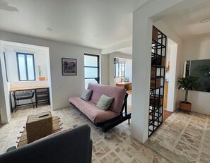 A modern living room with a sofa, a desk, and a staircase. - Apartment with AC in Colonia Reforma (pet friendly) 30 minutes from downtown (Oax.)