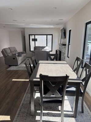 Un comedor moderno con una mesa y sillas de madera, un sofá gris y una chimenea.