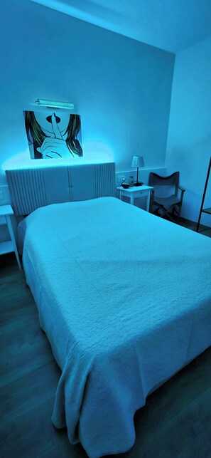 Une chambre Ă coucher avec un lit, une table de chevet, une lampe et une chaise.