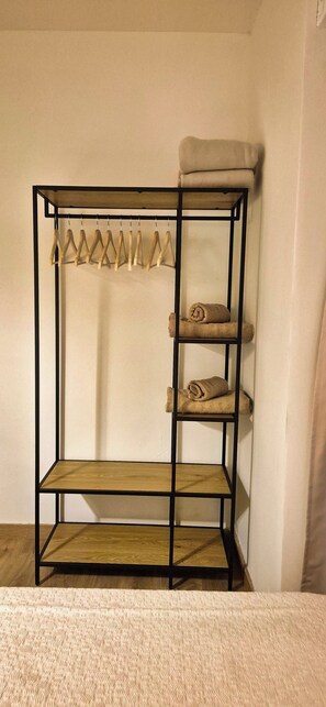A bunk bed with a wooden frame, a shelf with towels, and a hanging rack.