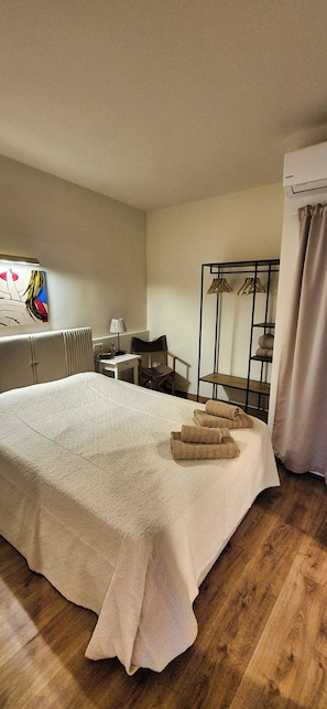 Une chambre dâhĂŽtel avec un grand lit, un bureau, une chaise, un radiateur et un porte-manteau fixĂ© au mur.