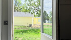A doorway leading to a backyard with a wooden deck and a green patterned rug. -     Rustic Spa Escape Near I-70 (Goodland)