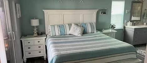 Quarto com cama, mesas de cabeceira, cômoda, espelho e decoração de parede com estrelas-do-mar.