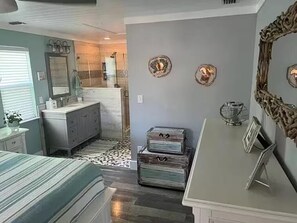 A bedroom with a bed, dresser, vanity, and a mirror. - Aqua Tide Retreat - Waterfront + Boatlift (Jensen Beach)