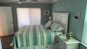 Een slaapkamer met een bed, een ladekast en een raam met zonwering.