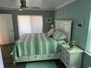 A bedroom with a bed, dresser, and a window with blinds. - Aqua Tide Retreat - Waterfront + Boatlift (Jensen Beach)