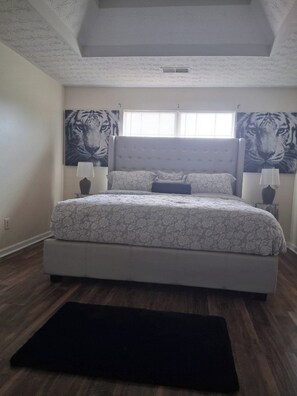 A bedroom with a bed, two wall-mounted lamps, and tiger-themed wall art. - Spacious 4-bedroom, 2.5 bath home in beautiful Fairburn with spacious living (Fairburn)
