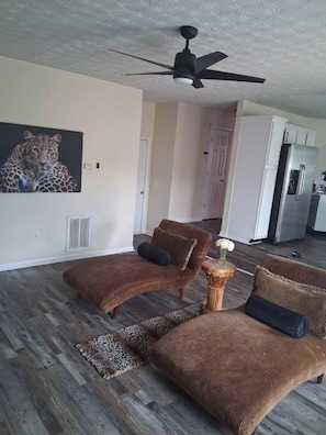 A living room with a ceiling fan, two brown sofas, a leopard print rug, and a painting of a leopard. - Spacious 4-bedroom, 2.5 bath home in beautiful Fairburn with spacious living (Fairburn)
