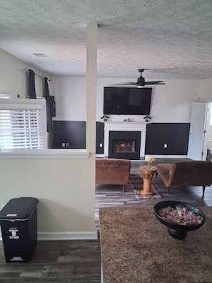 A living room with a fireplace, two sofas, a TV, and a ceiling fan. - Spacious 4-bedroom, 2.5 bath home in beautiful Fairburn with spacious living (Fairburn)