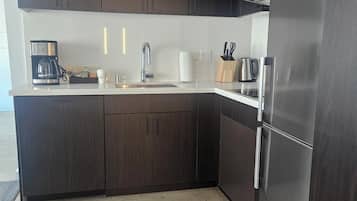 Una cucina moderna con mobili in legno scuro, elettrodomestici in acciaio inossidabile e un piano di lavoro bianco.