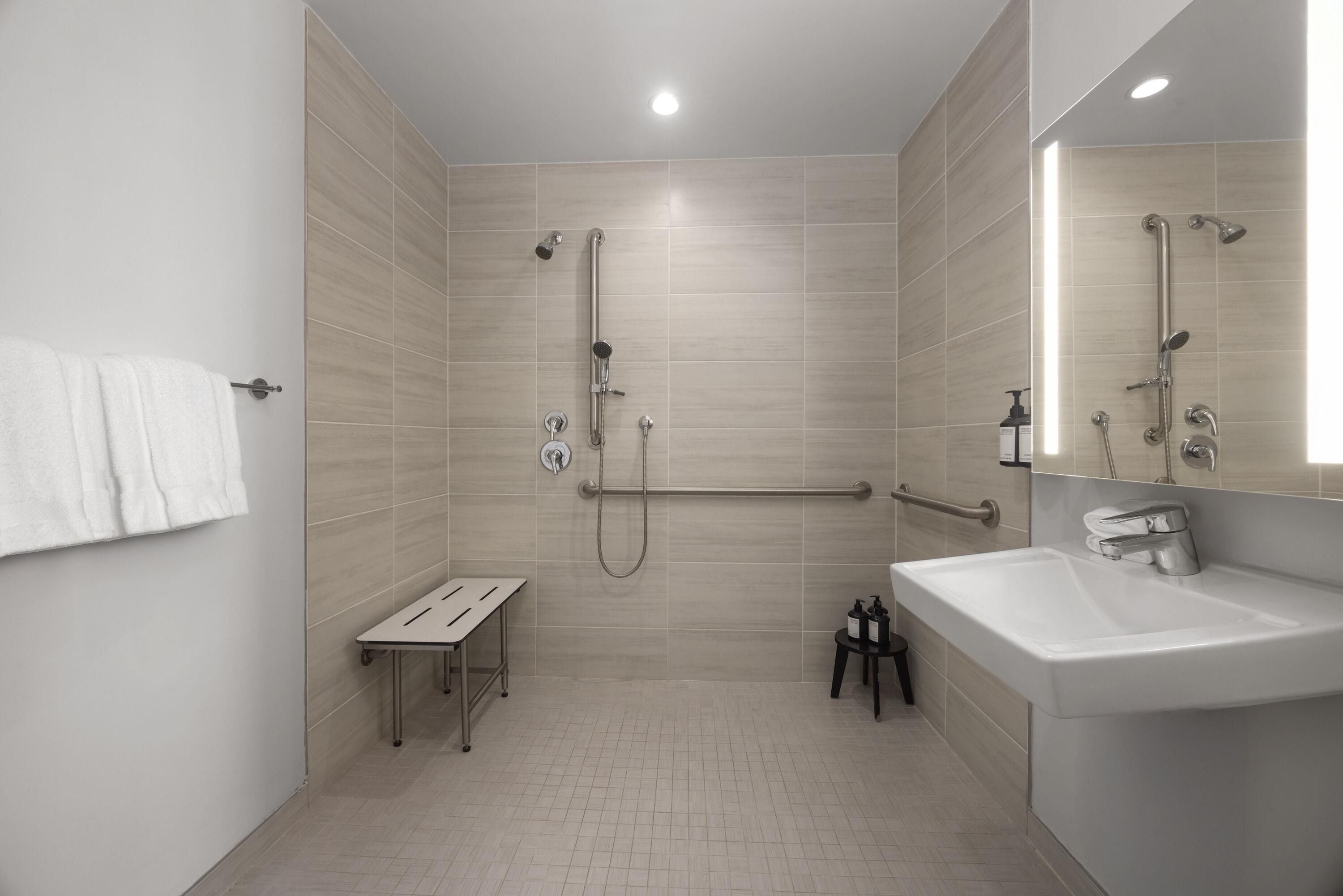 A modern bathroom with a shower, a sink, and a mirror.