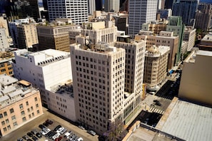 A high-rise building with a grid of windows, a central dome, and a parking lot with cars.