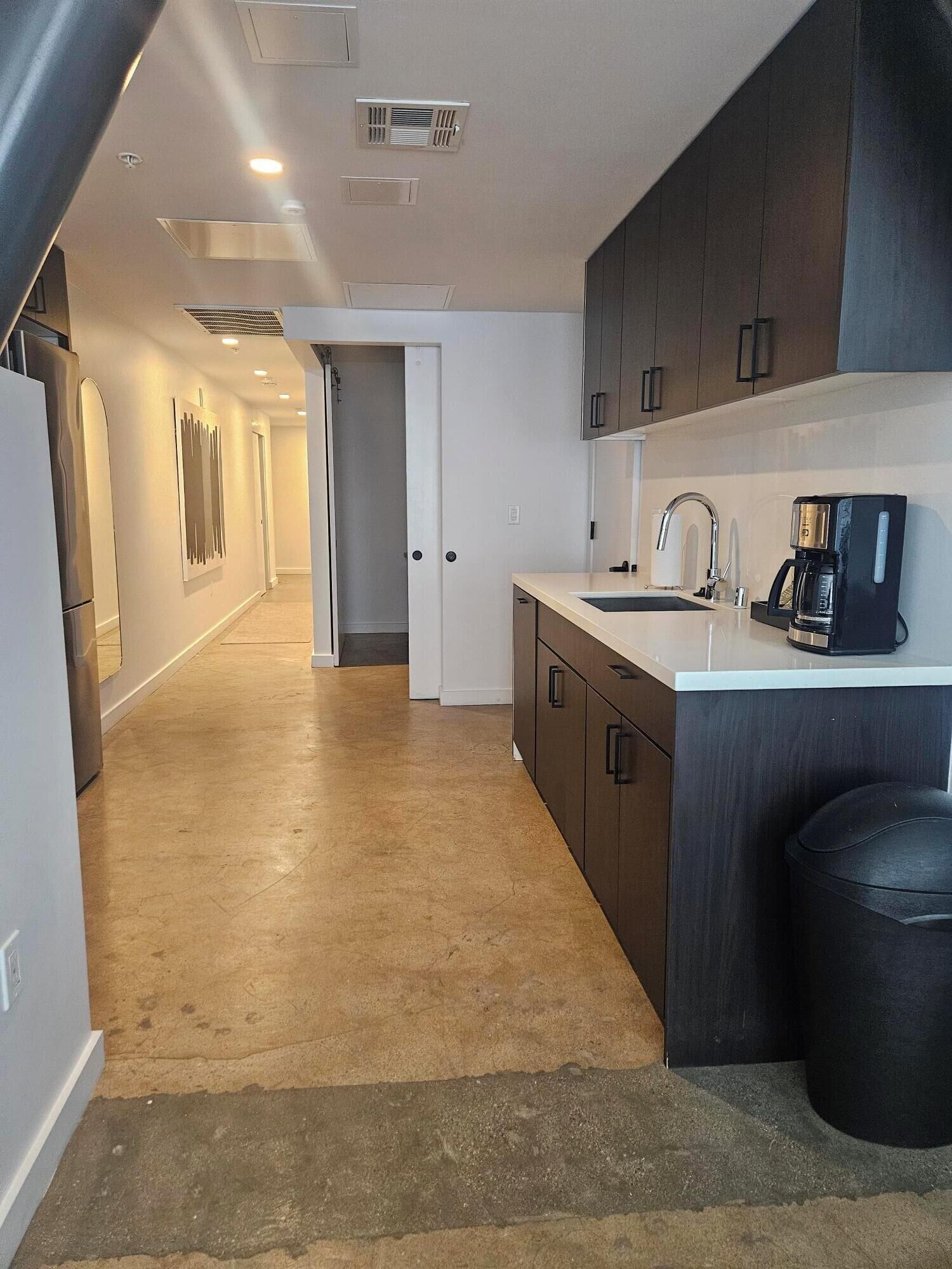 A modern kitchen with a central island, a built-in oven, and a coffee maker.