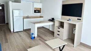 A compact kitchen with a refrigerator, microwave, and a small sink. There's a desk with a computer and a TV. - Baymont By Wyndham Lexington (Lexington)
