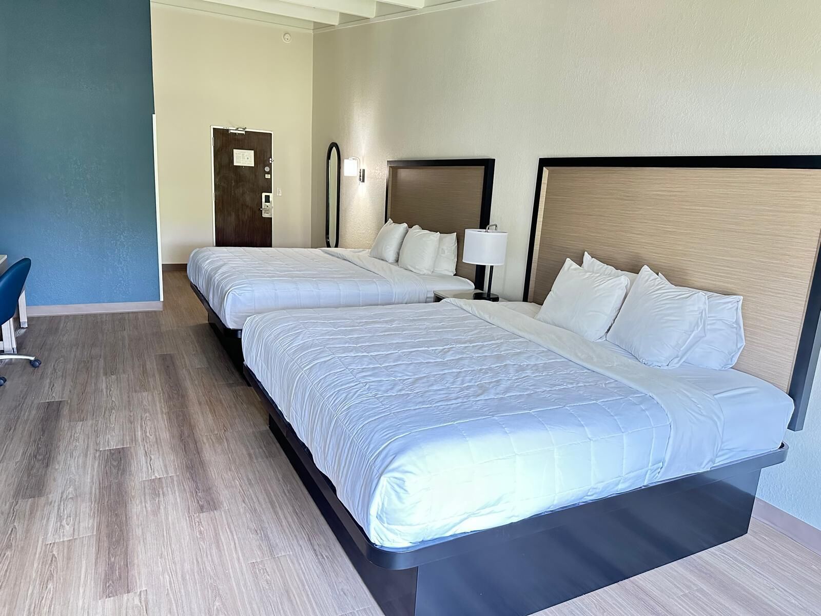 A hotel room with two beds, a desk, and a chair.