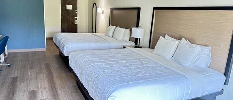 A hotel room with two beds, a desk, and a chair.