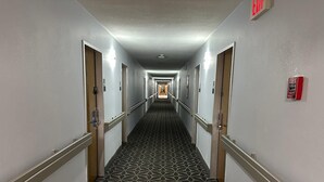 A hotel hallway with patterned carpet, doors, and a fire alarm on the wall. - Baymont By Wyndham Lexington (Lexington)