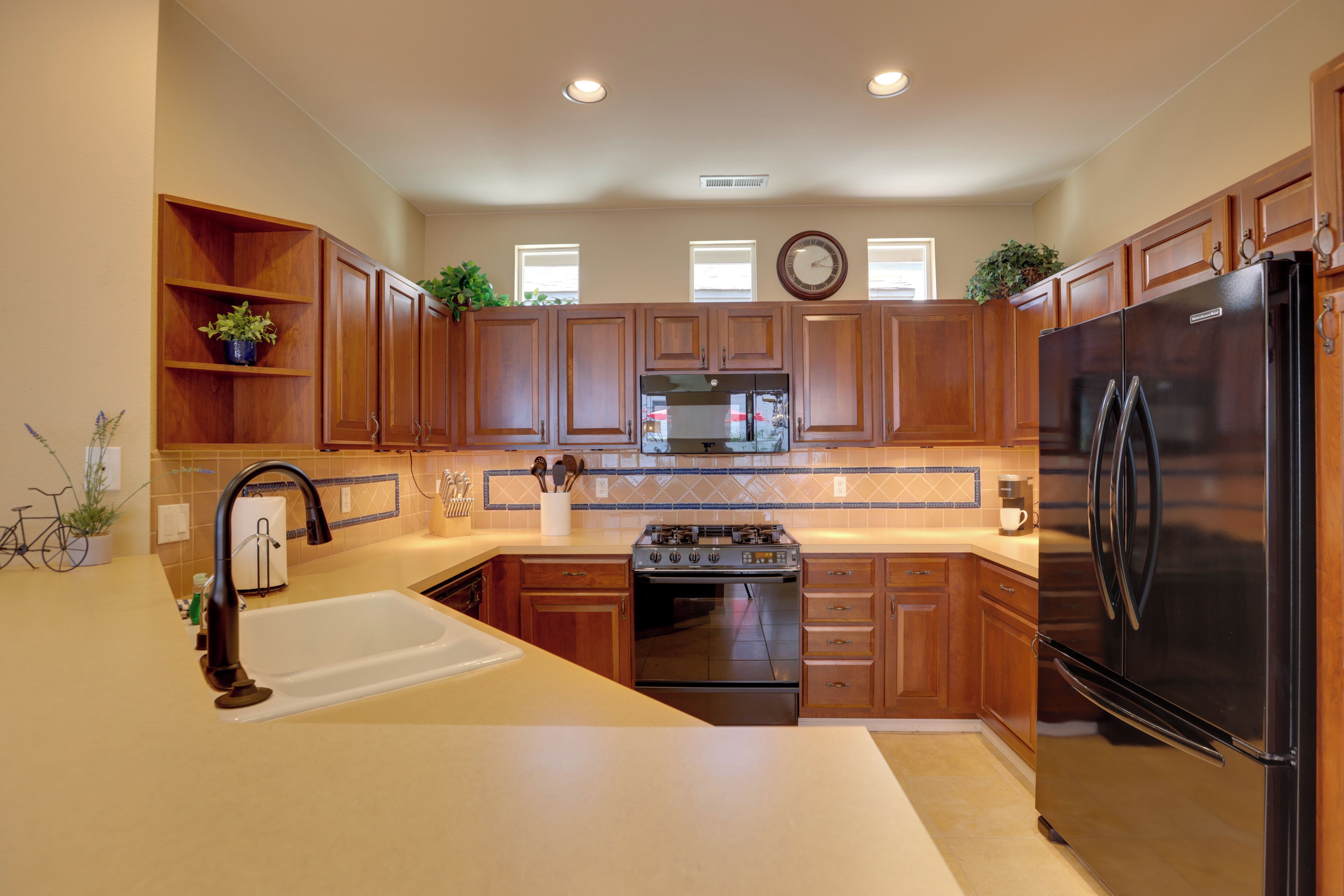 A kitchen with wooden cabinets, a stainless steel refrigerator, a sink, and a stove.