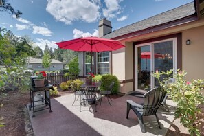 A patio with outdoor furniture, a red umbrella, and a potted plant. - Bend Home: Office, Garage, Parks, Seasonal Pool! (Bend)