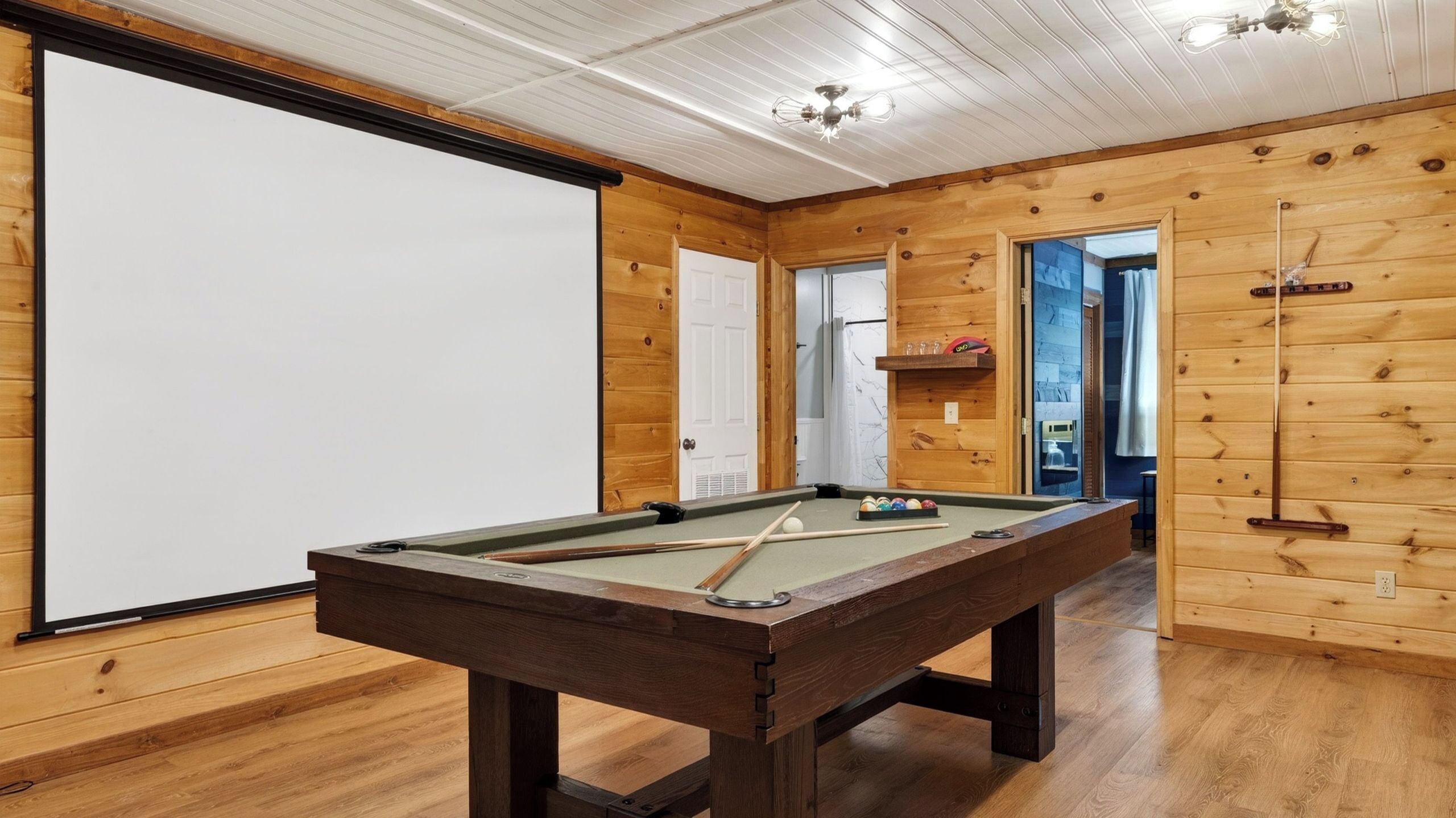 A pool table in a wooden room with a white ceiling and wooden walls.