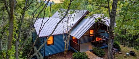 A cabin with a sloped roof, a porch, and a small deck.