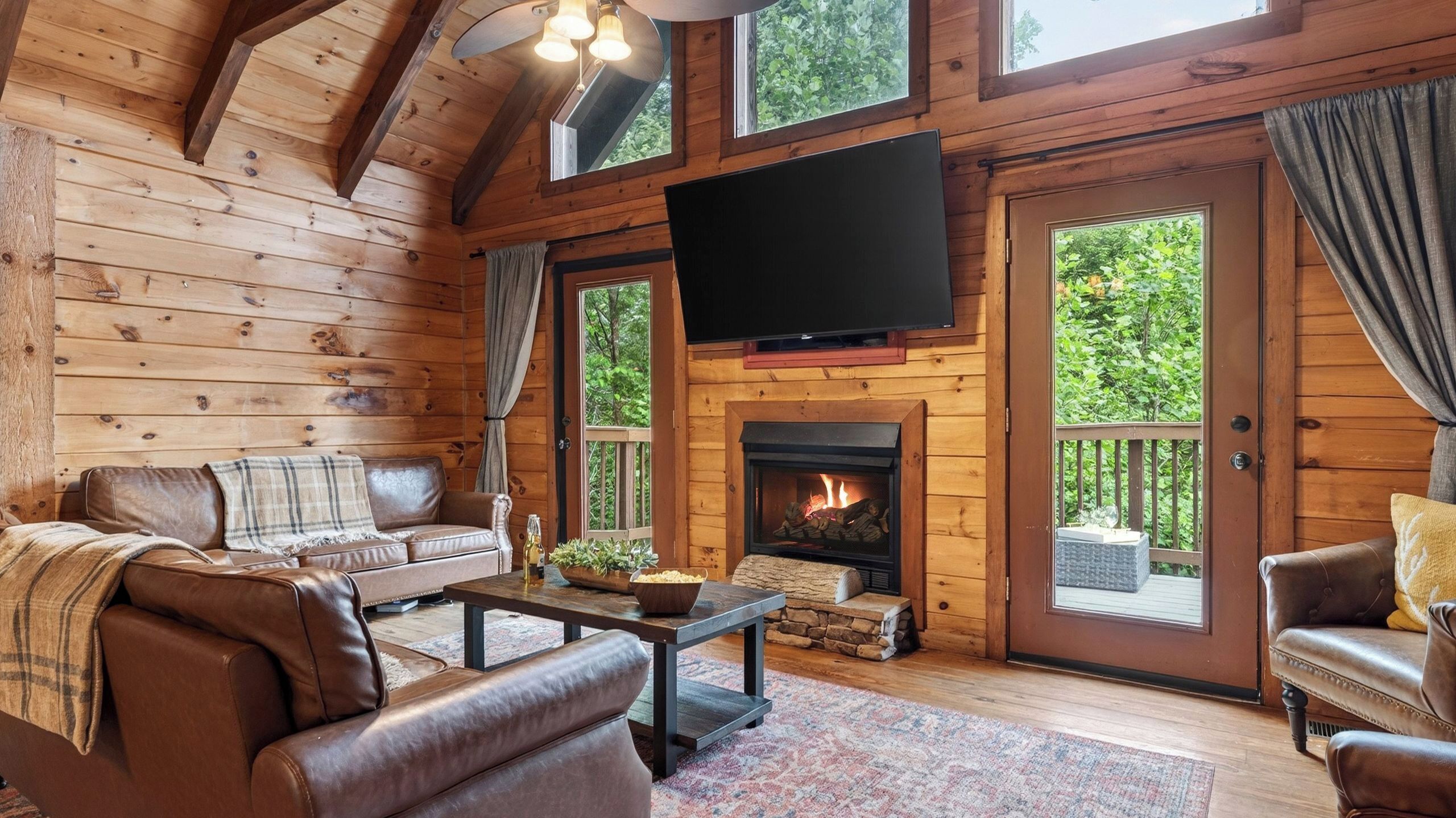 Un intérieur de chalet chaleureux avec une cheminée, des meubles en cuir et un téléviseur.