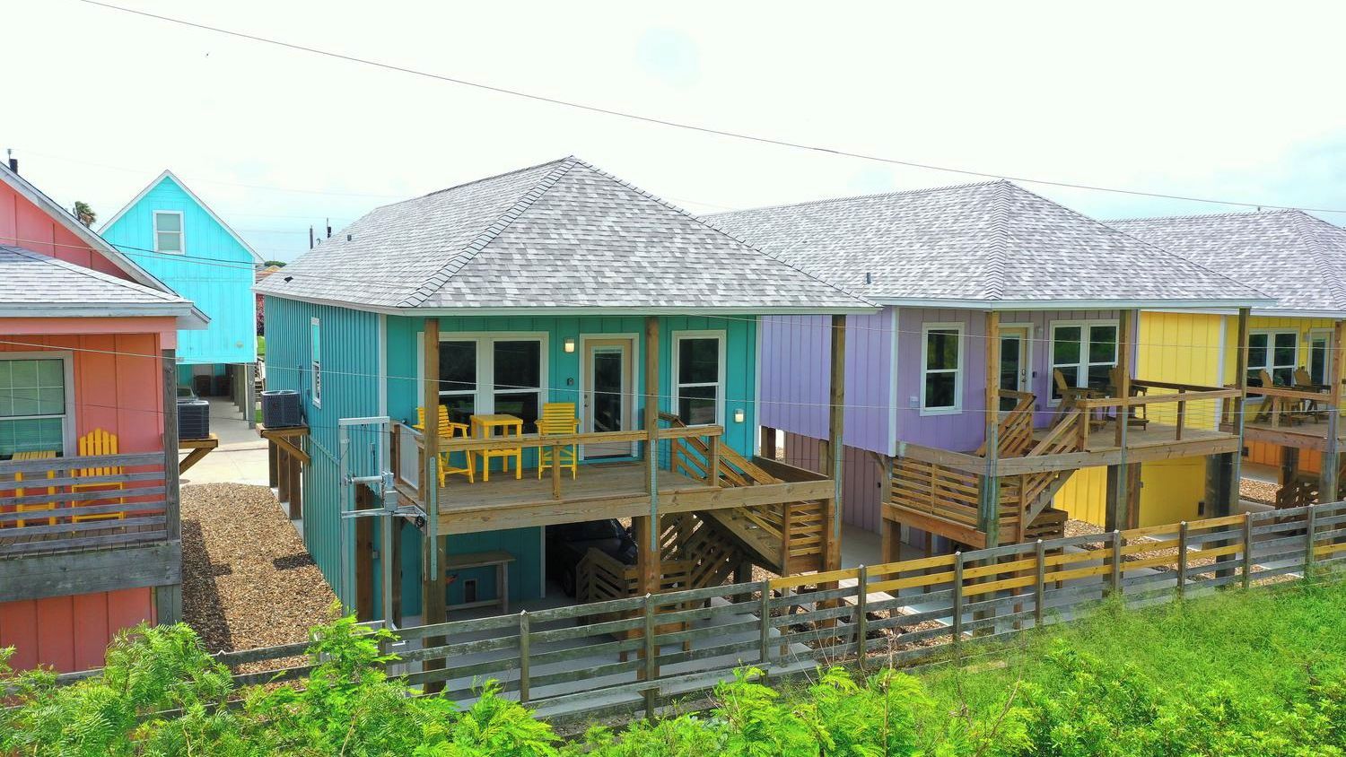 A multi-story building with a deck and stairs, surrounded by a wooden fence.