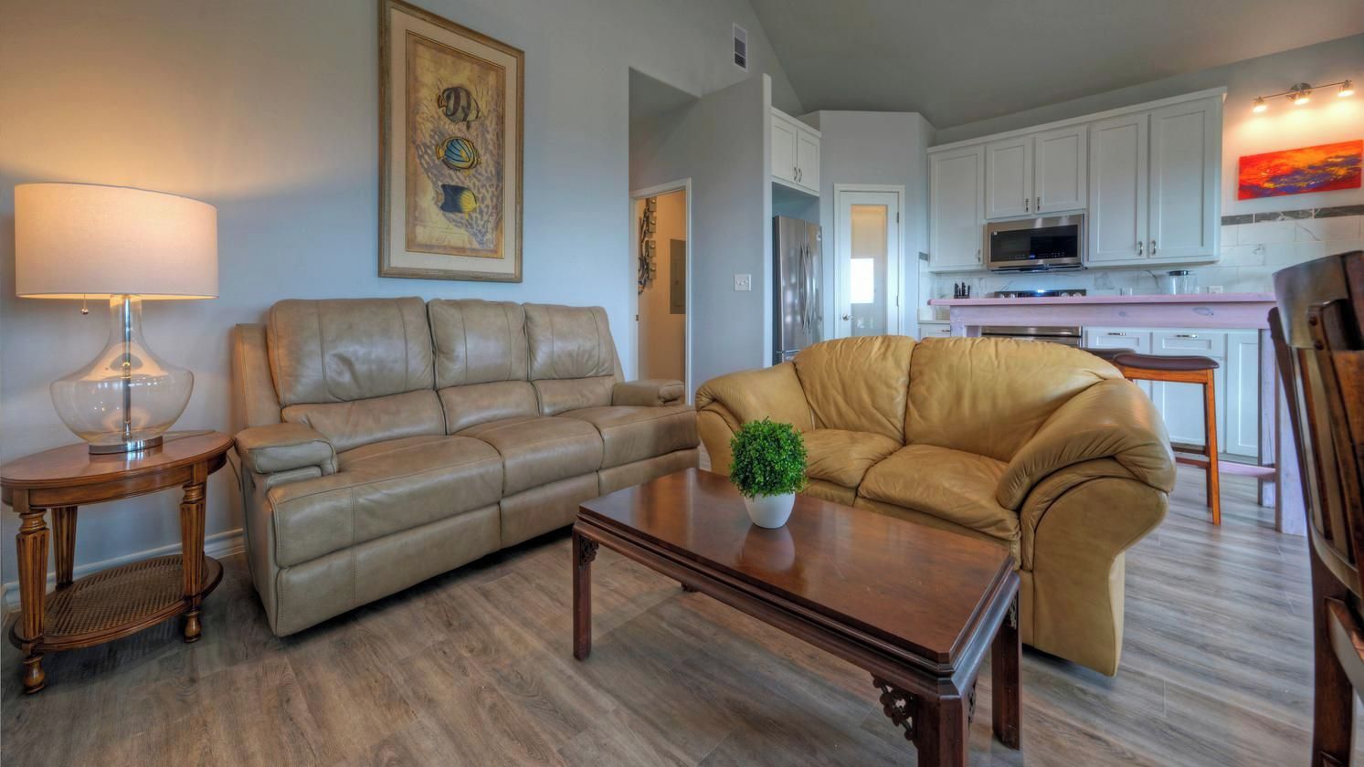 A living room with a sofa, a coffee table with a plant, a lamp, and a painting on the wall.