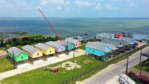 Una zona residencial costera con casas coloridas, un muelle y una carretera que lleva al agua.