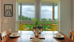 A dining table with a vase of green plants, two chairs, and a framed picture on the wall. - Sea Trout by Avantstay Community Pool + Dock Fishing + Kayaking Bayfront Escape (Corpus Christi)
