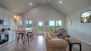 A spacious kitchen with a dining area, a large window, and a high ceiling. - Sea Trout by Avantstay Community Pool + Dock Fishing + Kayaking Bayfront Escape (Corpus Christi)
