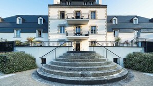 A multi-story building with a central entrance, a staircase leading to the entrance, and a small balcony on the upper floor. - Maison duplex avec wifi | Près de l'Aven (Pont-Aven)